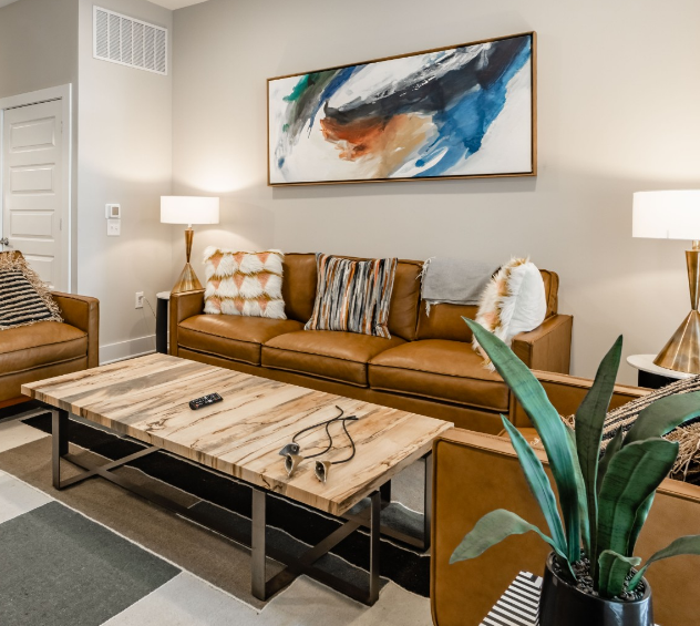 500 West Trade luxury apartment living room with couch, coffee table, rug, plant, and wall art
